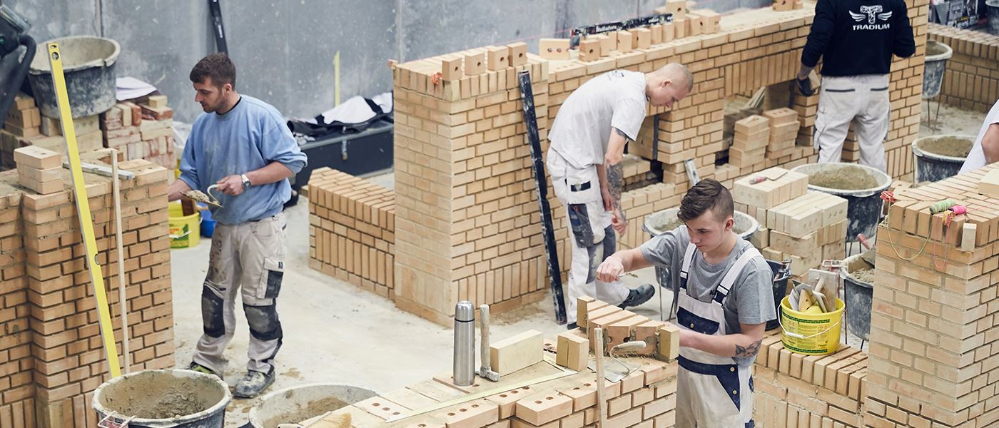 Murerelever arbejder med mursten på mureruddannelsen